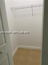Reach-in closet featuring white walls, neutral floor tile, and built-in wire shelving