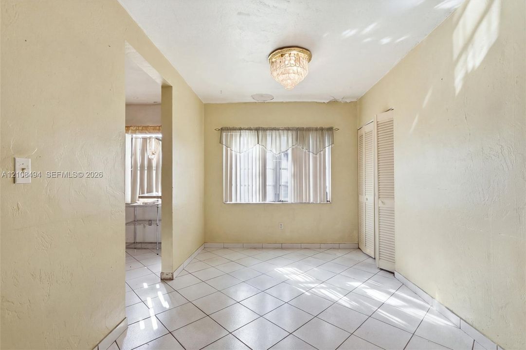 Neutral tile flooring, built-in louvered closet doors, and decorative crystal-style flush mount ceiling lighting