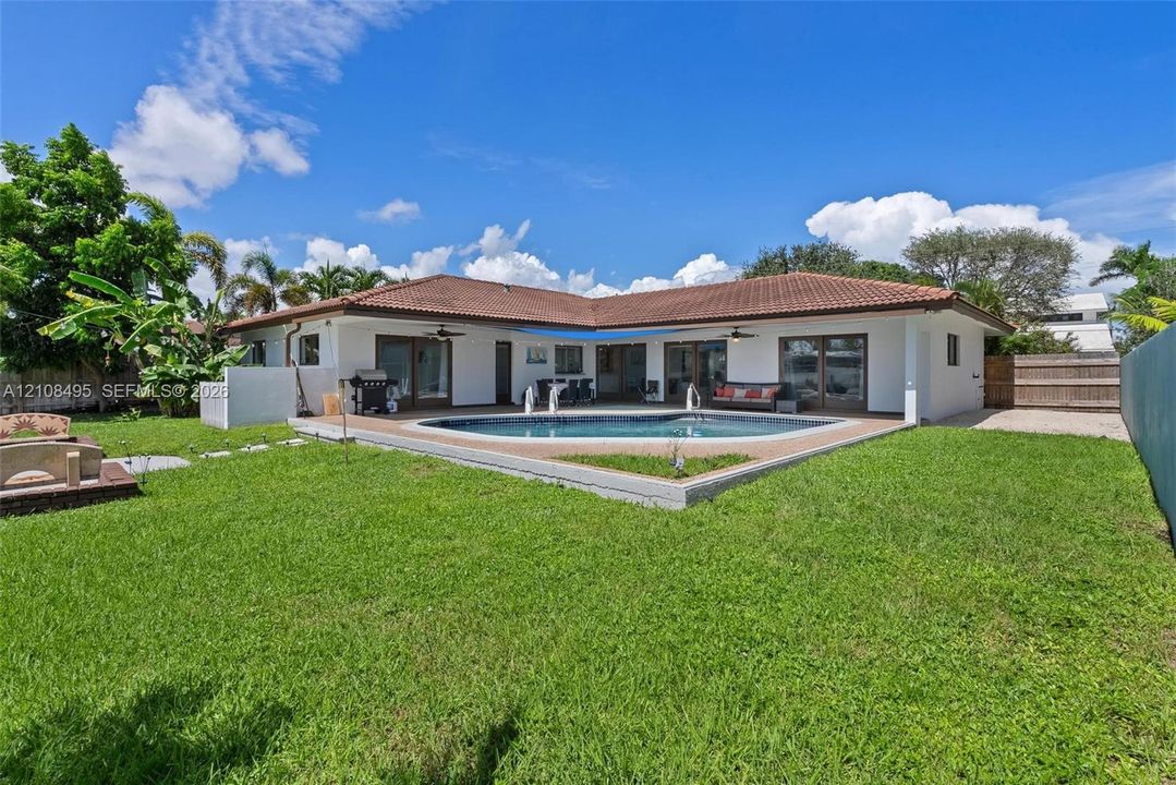 Backyard featuring an in-ground swimming pool, concrete patio, tiled roof, and perimeter fencing