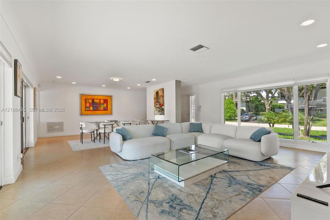 Open-concept living space featuring large-format ceramic tile flooring, expansive floor-to-ceiling windows, and recessed lighting