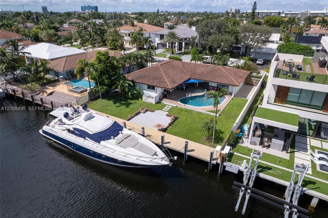Waterfront property featuring a private boat dock, swimming pool, manicured lawn, and hardscaped patio area