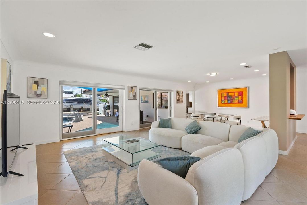 Open-concept living space featuring neutral tile flooring, recessed ceiling lighting, and expansive dual sliding glass doors