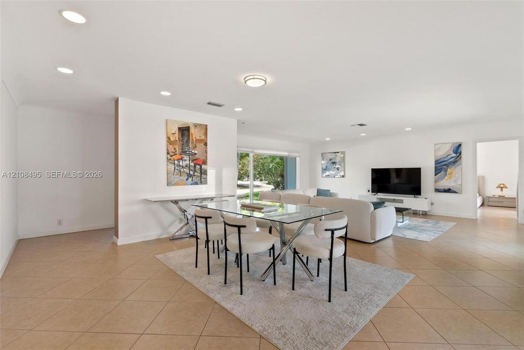 Open-concept living space featuring neutral ceramic tile flooring, recessed lighting, and large glass sliding doors