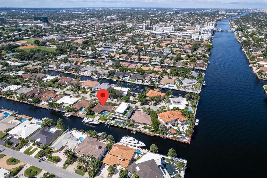 Aerial perspective of waterfront property featuring a private swimming pool, deep-water dockage, and direct canal access