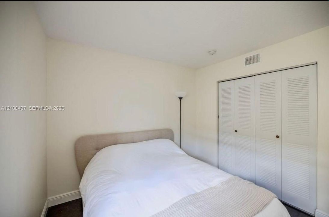 Neutral-toned interior featuring walls with a smooth finish and a closet with white louvered bifold doors