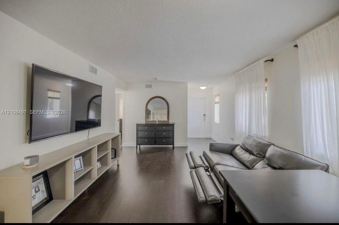 Living space featuring wood-finish flooring, white walls, and built-in shelving