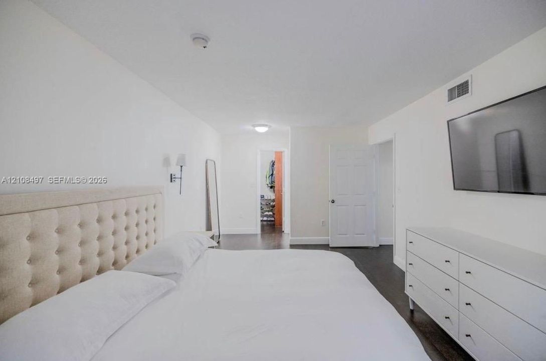 Neutral color palette featuring dark wood-finish flooring, white walls, flush-mount ceiling lighting, and wall-mounted sconce fixtures