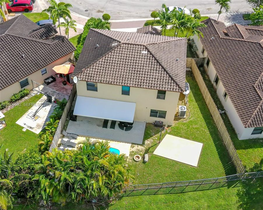 Two-story residence featuring a tile roof, covered rear patio, fenced backyard, swimming pool, and concrete hardscaping