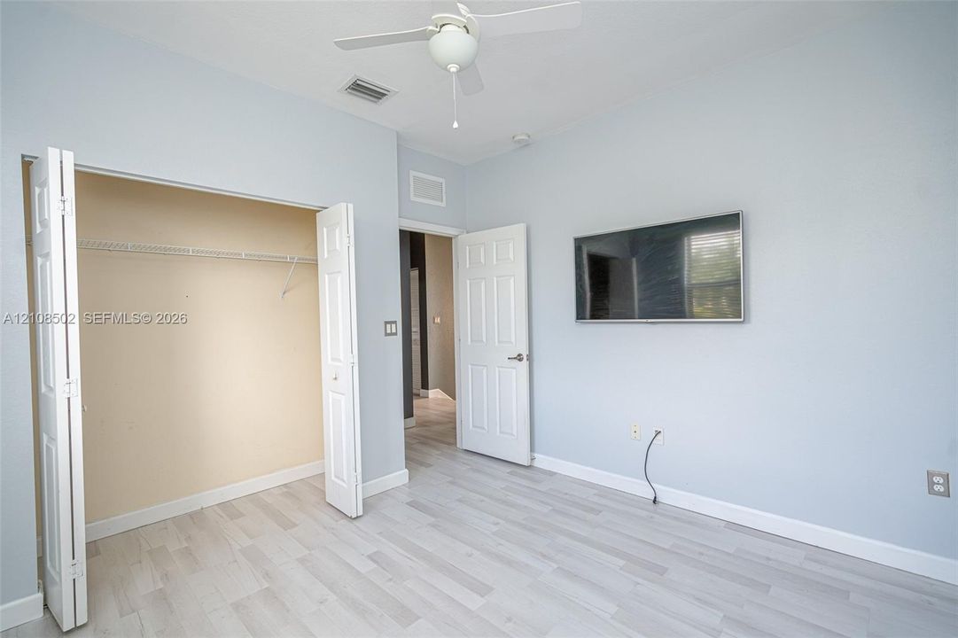 Room featuring wood-finish flooring, a ceiling fan with integrated lighting, and a closet with bifold doors