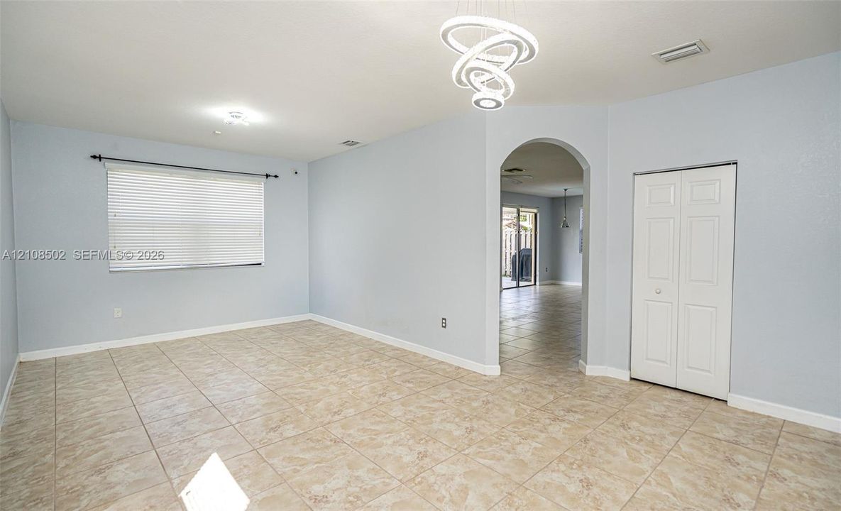 Interior space featuring tile flooring, modern sculptural LED chandelier, arched entryway, and double-door closet
