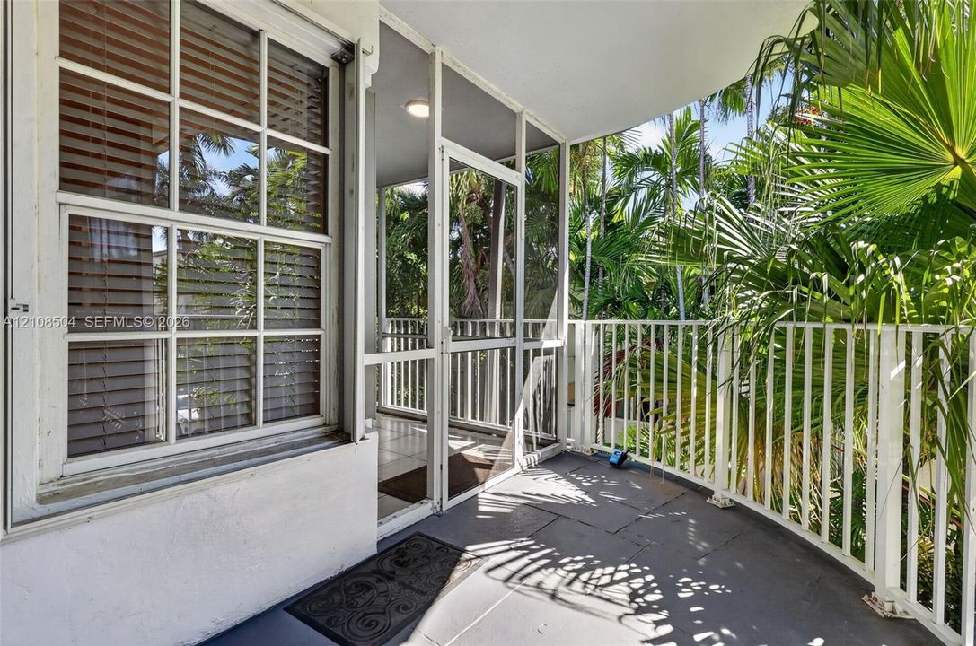 Covered balcony featuring tile flooring, white metal railing, and a screen enclosure
