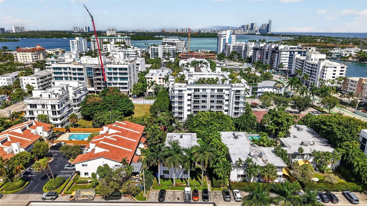 Aerial perspective of a multi-residential enclave featuring orange-tiled rooflines, manicured palm landscaping, asphalt surface parking, and perimeter hedging