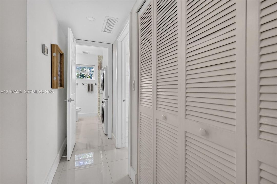 Hallway featuring full-height louvered closet doors, polished tile flooring, and recessed ceiling lighting