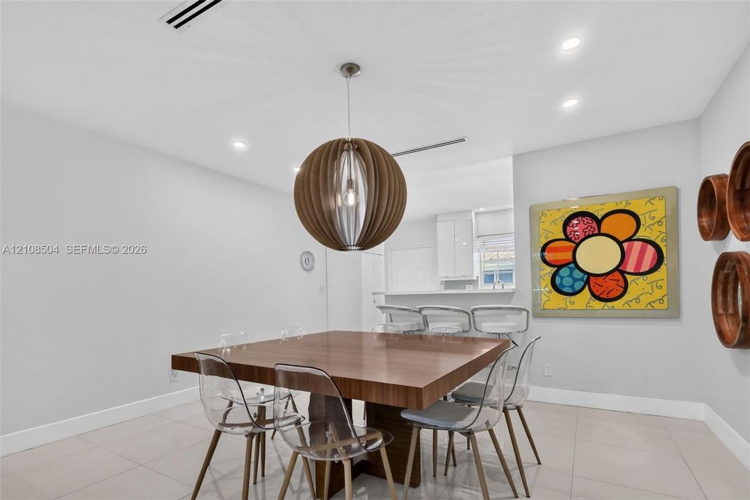 Dining area featuring large-format tile flooring, recessed ceiling lighting, and a spherical wooden pendant fixture