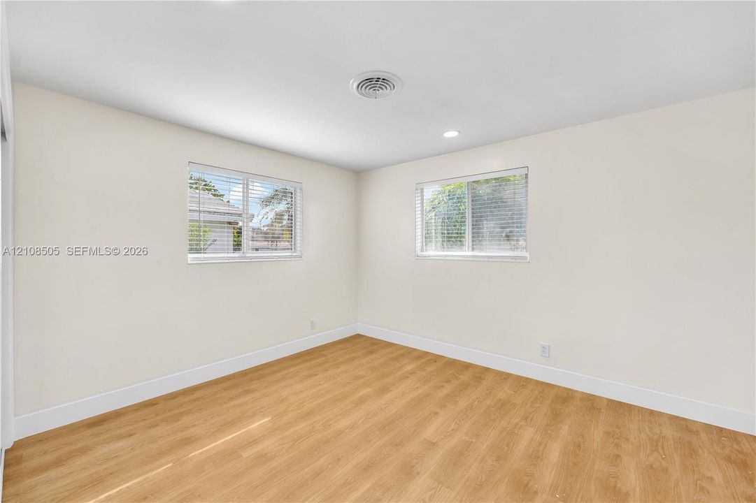 Neutral-toned interior featuring wood-finish flooring, recessed lighting, and dual windows with horizontal blinds