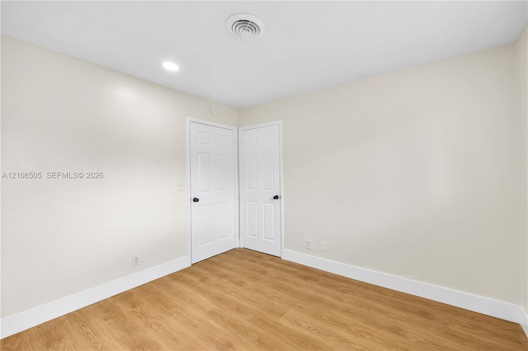 Neutral wall color, wood-finish flooring, recessed lighting, and two interior doors with matte black hardware