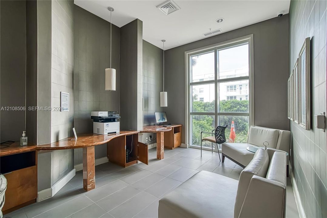 Built-in stone-top desk with integrated wood cabinetry, floor-to-ceiling multi-pane window, large-format tile flooring, and two modern pendant light fixtures