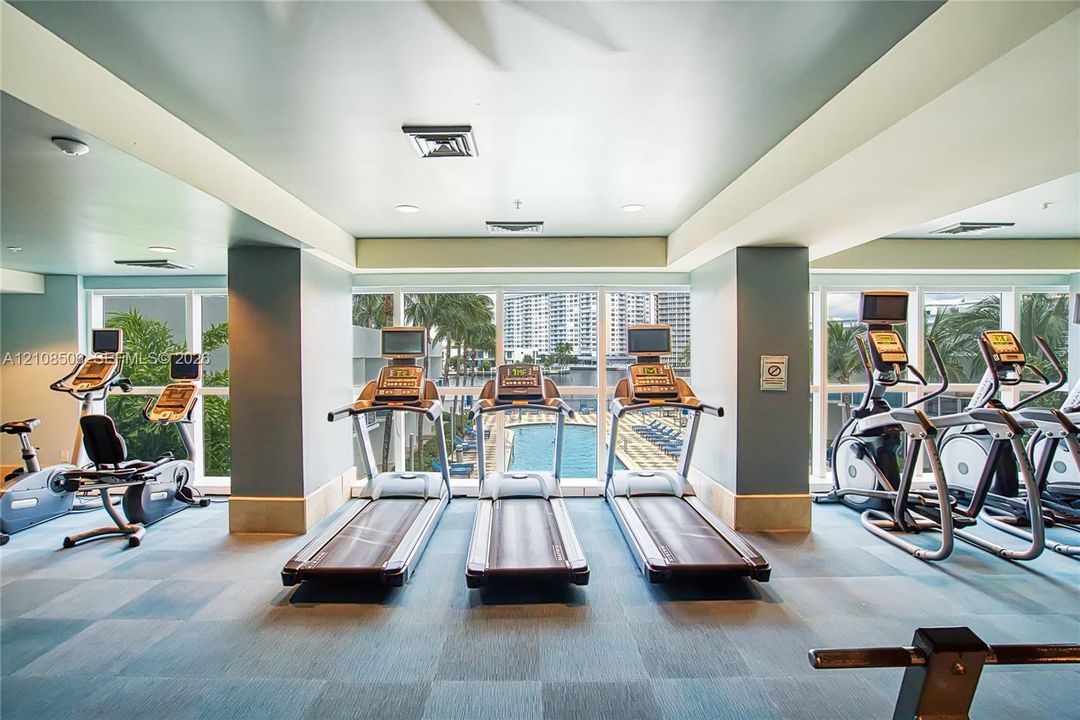 Fitness center featuring expansive floor-to-ceiling windows, blue tile flooring, and integrated wall mirrors