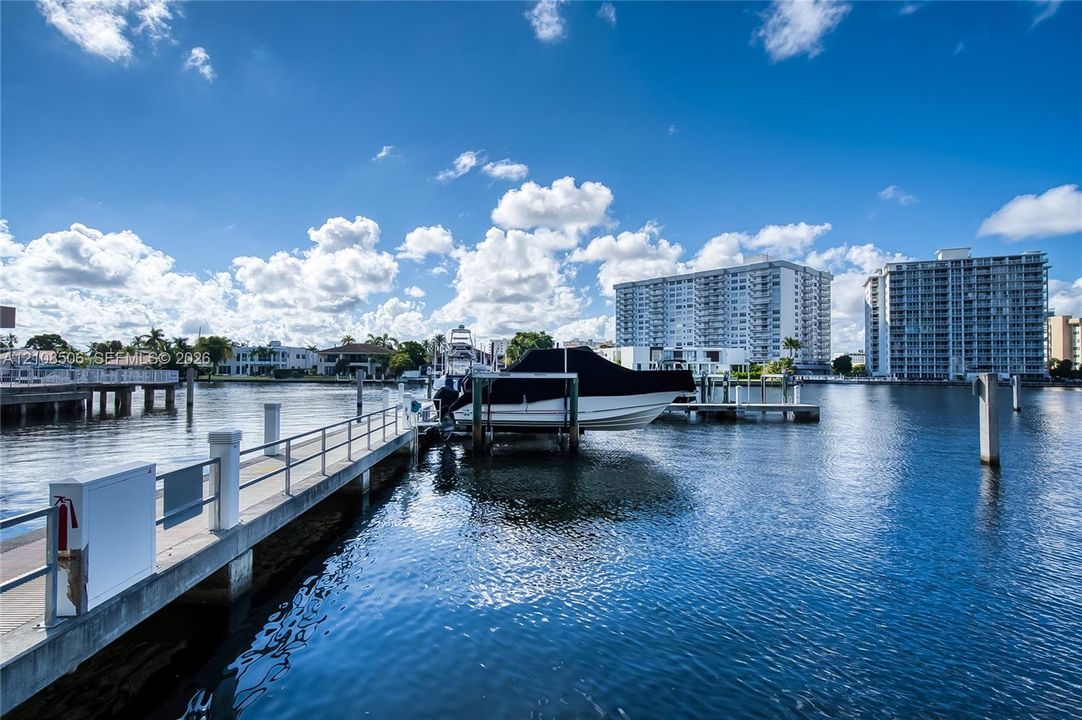 Waterfront location featuring a concrete dock, integrated boat lift, and metal railing
