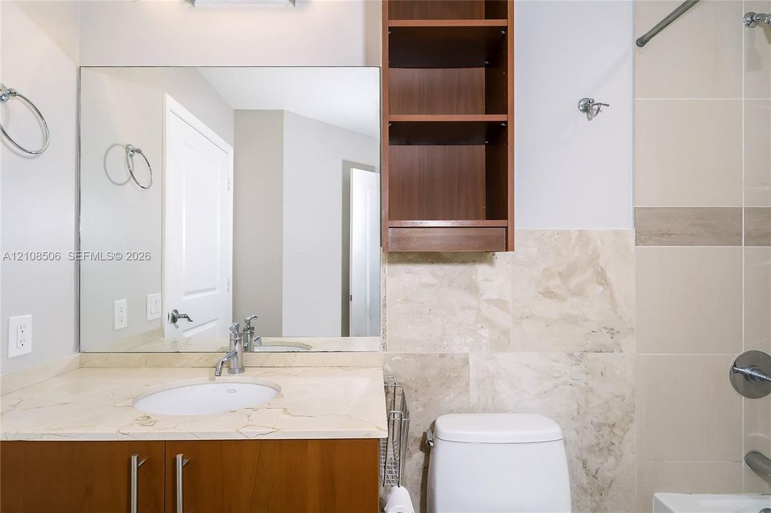 Bathroom featuring a vanity with stone-finish countertop, integrated oval sink, and wood-finish cabinetry