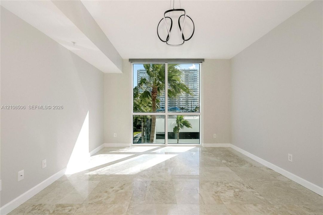 Neutral-toned space featuring polished stone flooring, floor-to-ceiling windows, and a modern geometric pendant light fixture