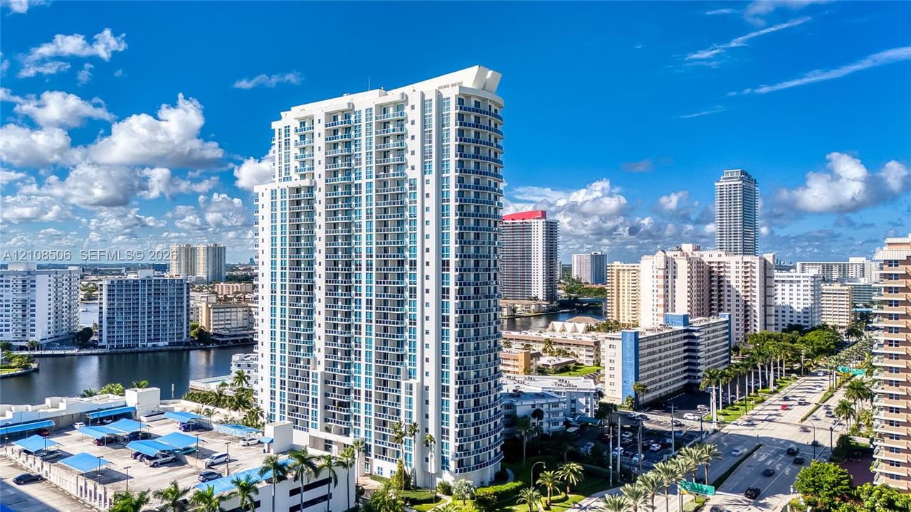 High-rise architectural structure featuring glass-paneled balconies and a multi-level parking facility