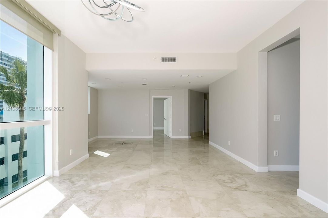 Floor-to-ceiling windows, polished stone tile flooring, modern circular chandelier, and recessed lighting