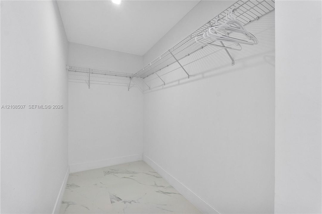 Walk-in closet featuring stone-patterned tile flooring and wrap-around wire shelving