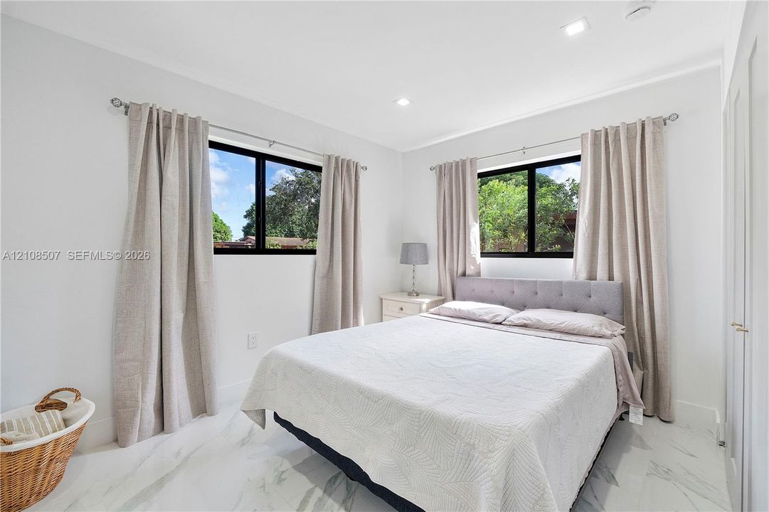 Neutral-toned interior featuring recessed lighting, polished stone-finish flooring, and black-framed windows
