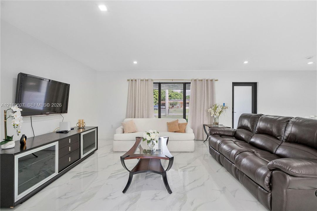 Living area featuring large-format tile flooring with a neutral veined pattern and recessed ceiling lighting