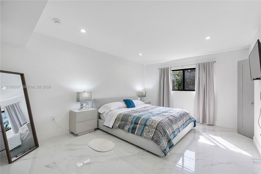 Large-format polished stone flooring, recessed ceiling lighting, and a single window with dark-toned framing
