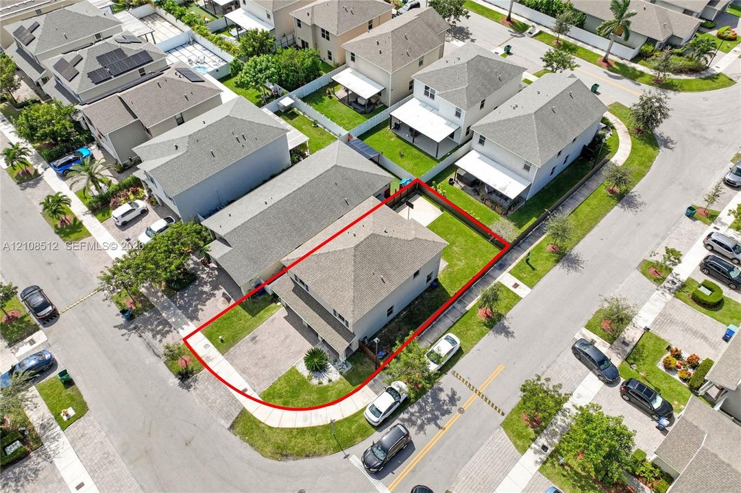 Two-story residence featuring a hip roof, paver driveway, and enclosed backyard with a concrete patio