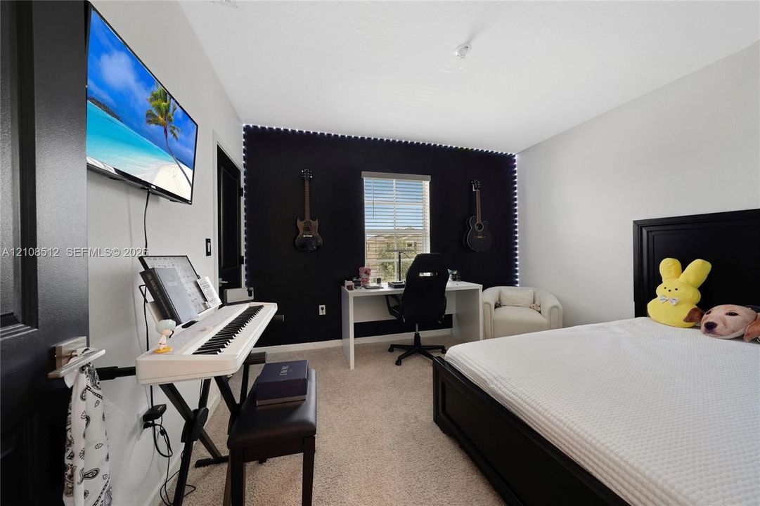 Bedroom featuring neutral-toned carpeting, high-contrast accent wall, and a single-pane window with horizontal blinds