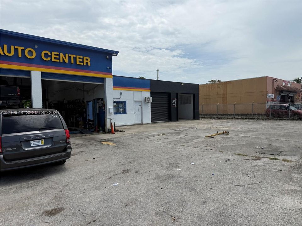 Commercial facility featuring multi-bay service access, roll-up security doors, concrete exterior wall construction, and a paved exterior lot