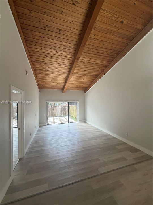 Vaulted wood-plank ceiling with exposed structural beams and wide-plank wood-finish flooring