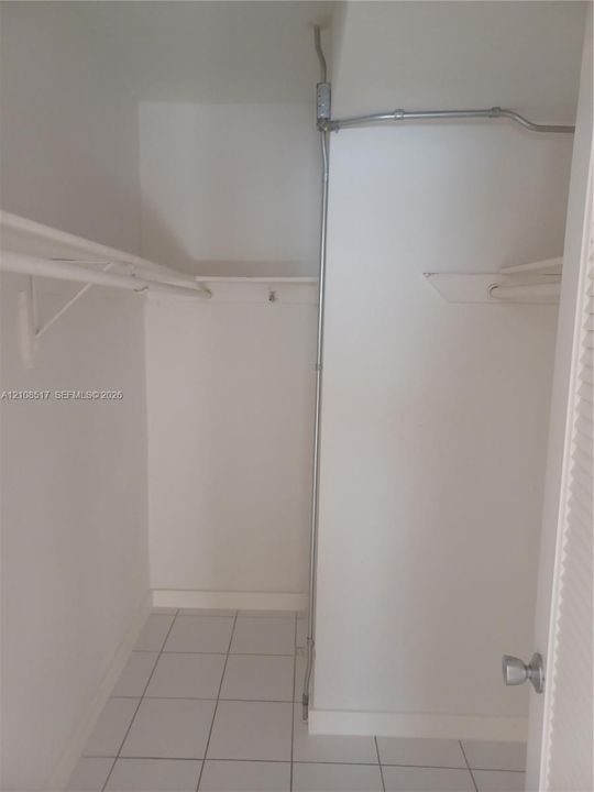 Storage area featuring white tile flooring, built-in metal shelving, and a louvered door