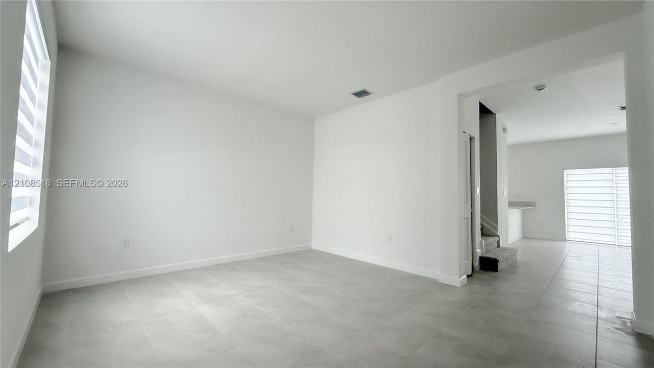 Large-format tile flooring, neutral wall tones, and tiered window treatments featuring light-filtering shades