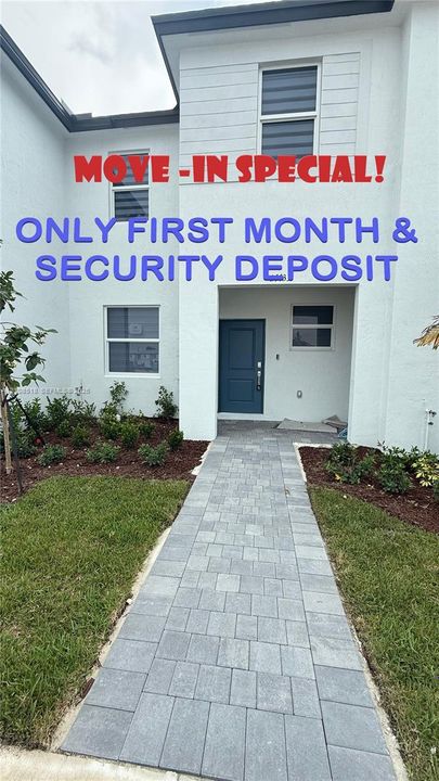 Two-story exterior featuring white stucco siding, a recessed entryway with a solid door, and a paved stone walkway