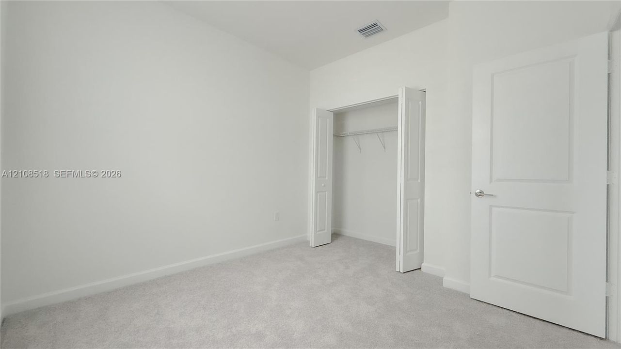Neutral-toned carpeting, two-panel interior door, and walk-in closet with built-in shelving