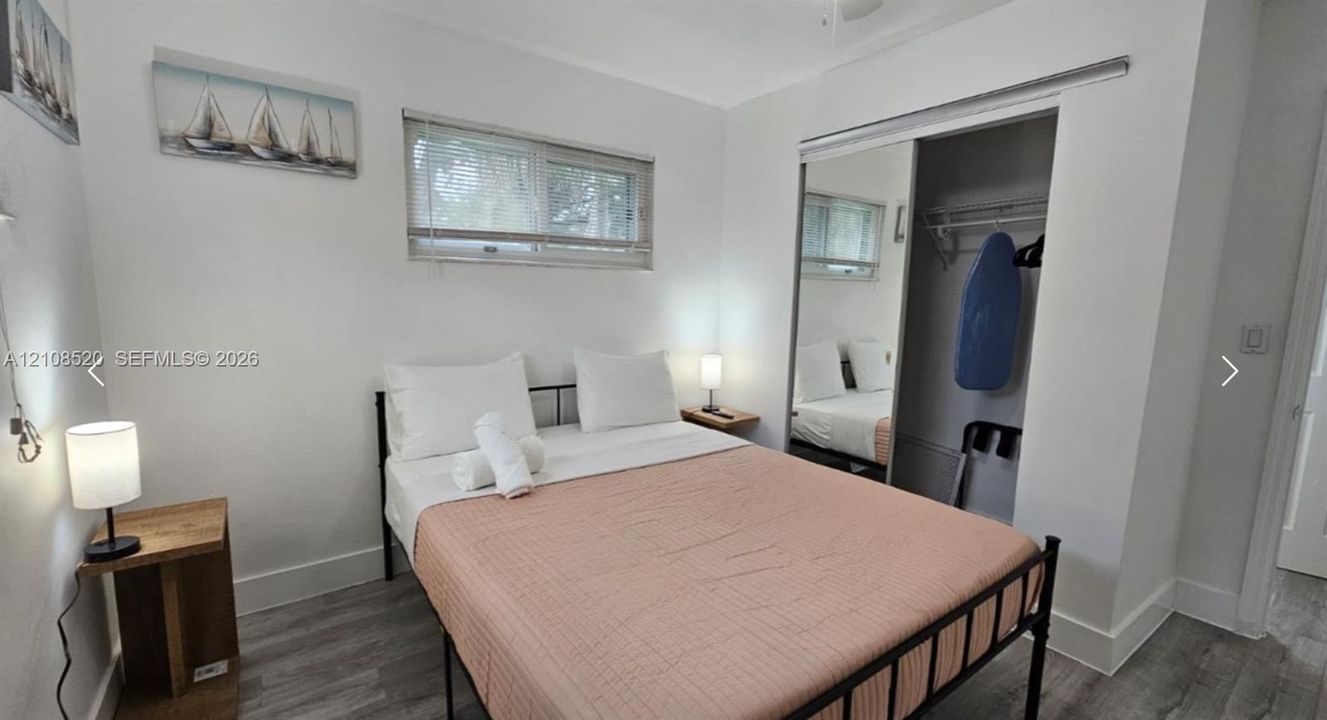 Room featuring wood-finish flooring, sliding mirror-door closet with integrated shelving, and a horizontal sliding window