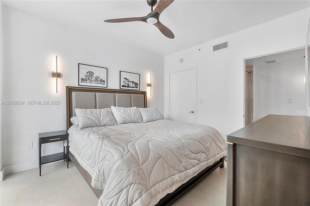 Room featuring a matte-finish three-blade ceiling fan, vertical wall-mounted lighting fixtures, and neutral flooring