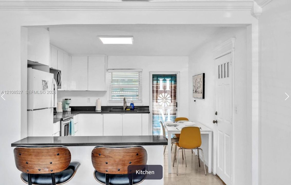 Kitchen featuring white cabinetry, solid-surface dark countertops, a breakfast bar, and tile flooring