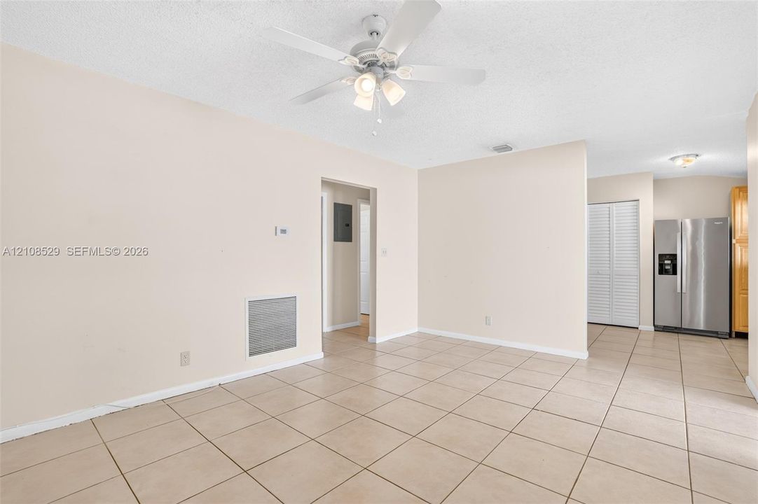Open interior space featuring neutral tile flooring, a multi-light ceiling fan, and a stainless steel refrigerator