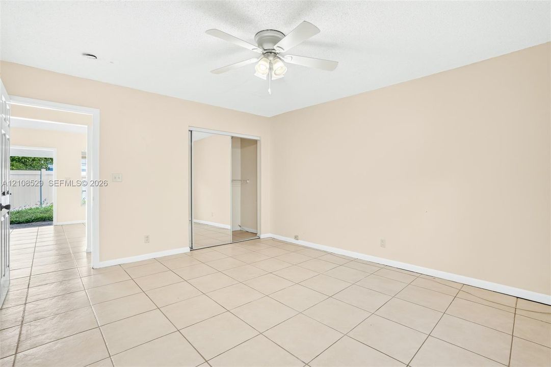 Neutral interior space featuring tile flooring, a ceiling fan with integrated lighting, and a closet with mirrored sliding doors