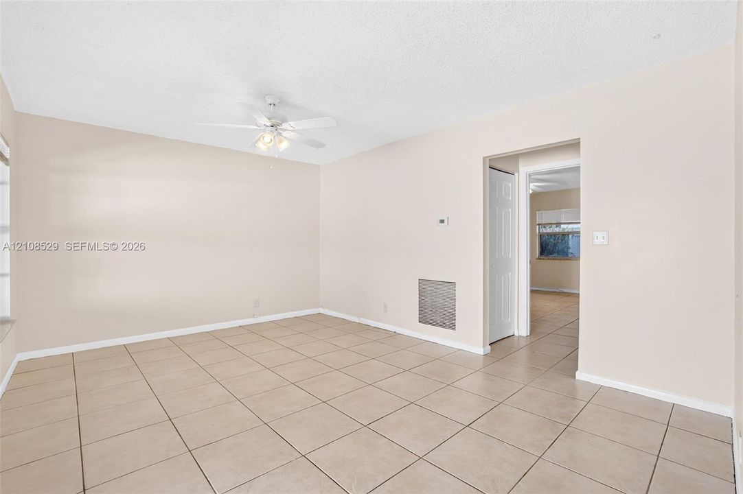Neutral-toned interior featuring ceramic tile flooring, a white ceiling fan with integrated lighting, and a textured ceiling finish