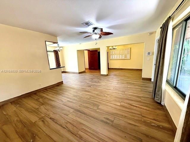 Open-concept interior featuring wood-finish flooring, a ceiling fan, sliding glass doors, and recessed pass-through window