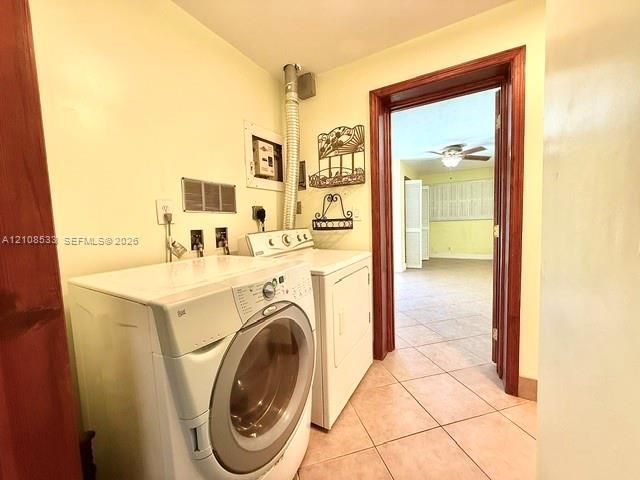 Dedicated laundry space featuring ceramic tile flooring and wood-trim door casing