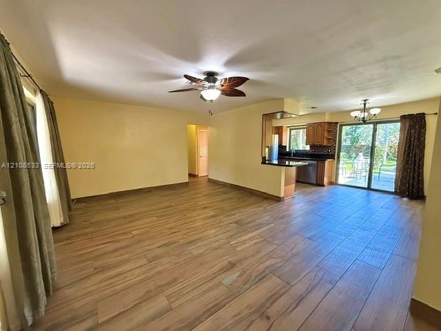 Open-concept interior featuring wood-finish tile flooring, a palm-leaf style ceiling fan, dark cabinetry, and sliding glass doors