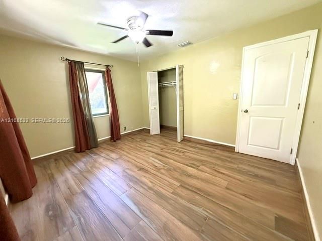 Wood-finish flooring, ceiling fan with integrated lighting, closet with bifold doors, and panel-style interior door