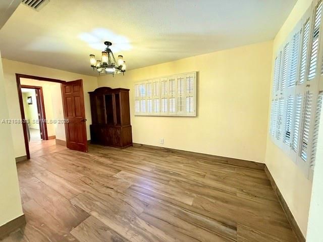 Wood-finish flooring throughout, white plantation shutters, and a multi-light chandelier